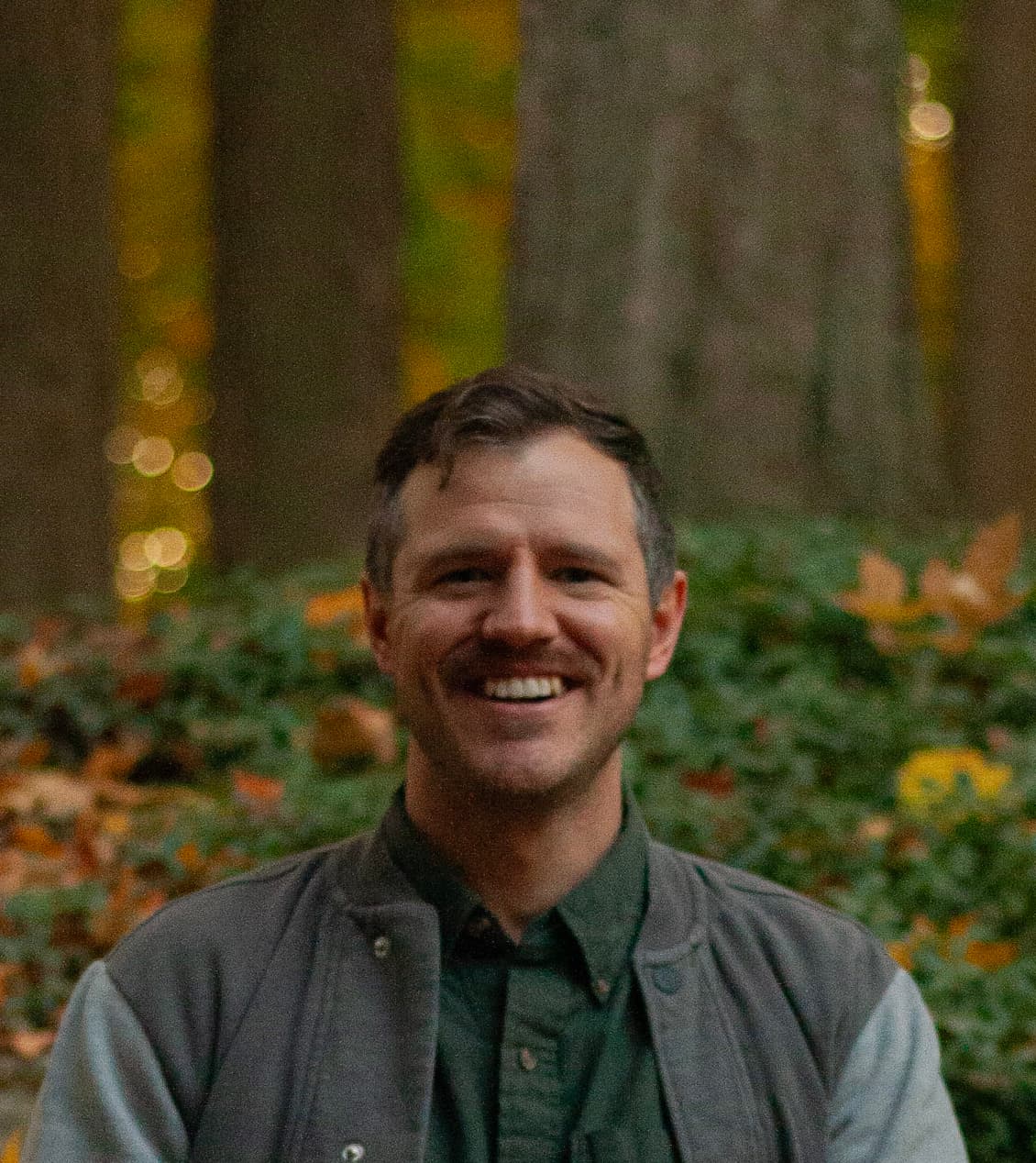 Andrew Van Dyke smiling in an autumn forest